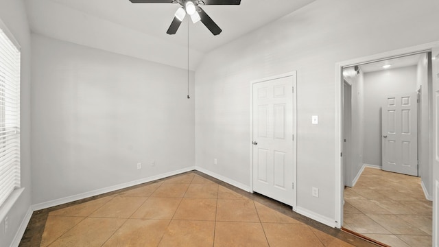 unfurnished bedroom featuring baseboards, light tile patterned floors, and a ceiling fan