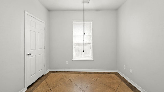 spare room with dark tile patterned floors, visible vents, a healthy amount of sunlight, and baseboards