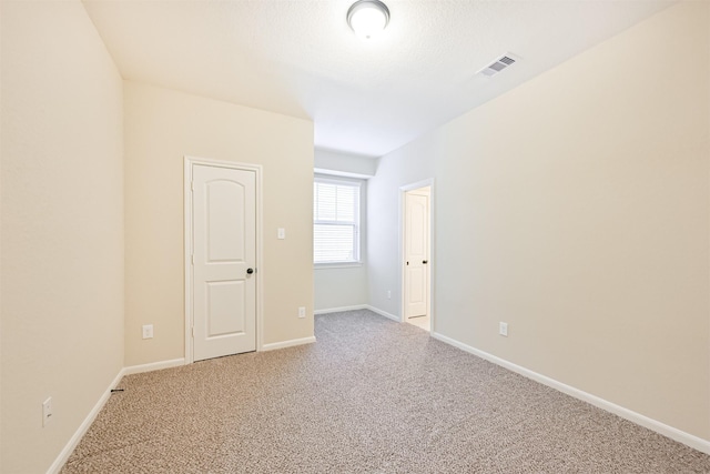 empty room with light colored carpet, visible vents, and baseboards