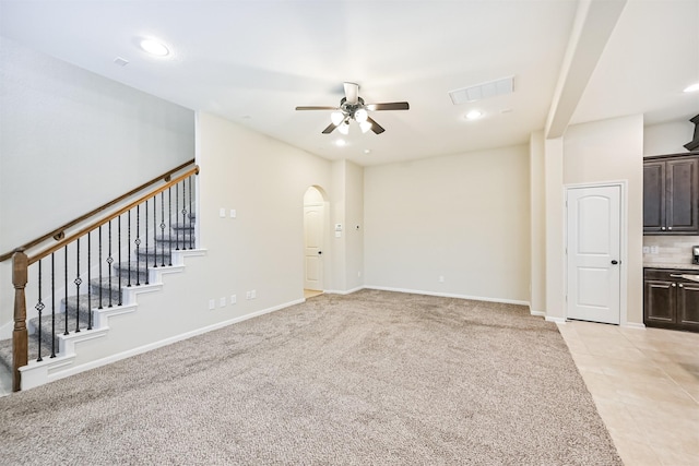 unfurnished living room with visible vents, light carpet, ceiling fan, and stairs
