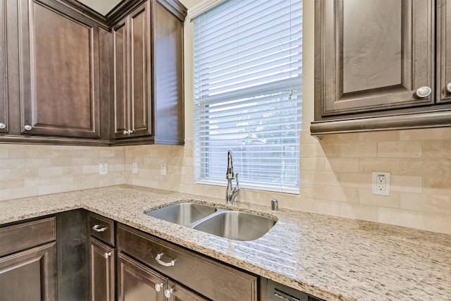 kitchen featuring backsplash, a sink, and dark brown cabinets