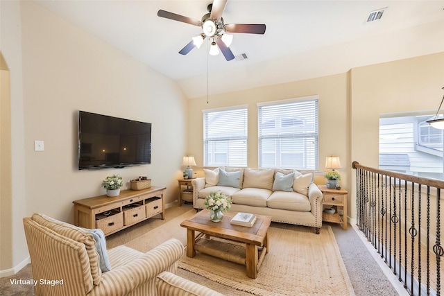 living room featuring a ceiling fan, visible vents, light carpet, and baseboards
