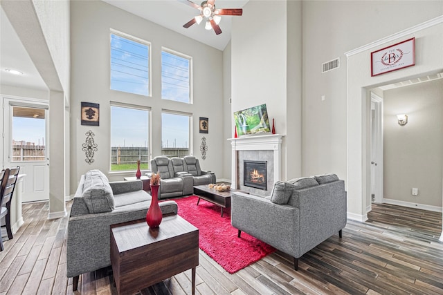 20535 Kohle Springs Ln, Cypress, TX 77433 - living area with visible vents, ceiling fan, wood finished floors, a tiled fireplace, and a high ceiling