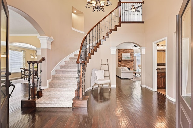 entrance foyer with wood-type flooring, arched walkways, baseboards, and a towering ceiling