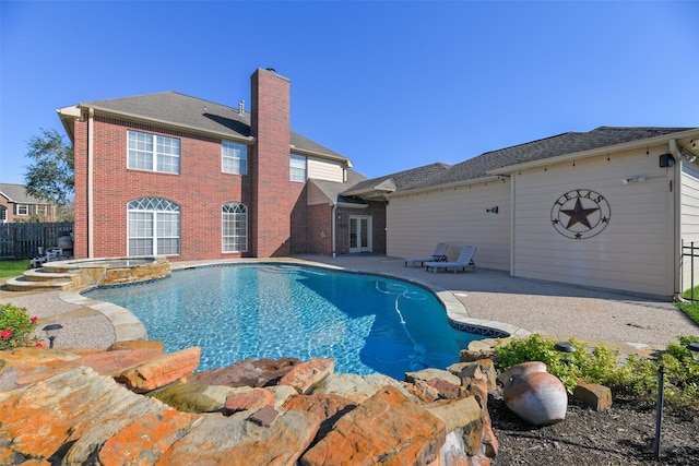 view of pool featuring french doors, fence, a patio, and a pool with connected hot tub