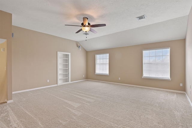 empty room with carpet flooring, a ceiling fan, baseboards, and vaulted ceiling