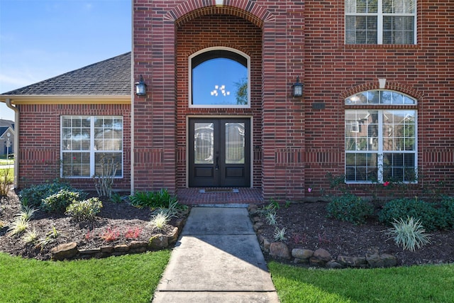 doorway to property with brick siding, roof with shingles, and french doors