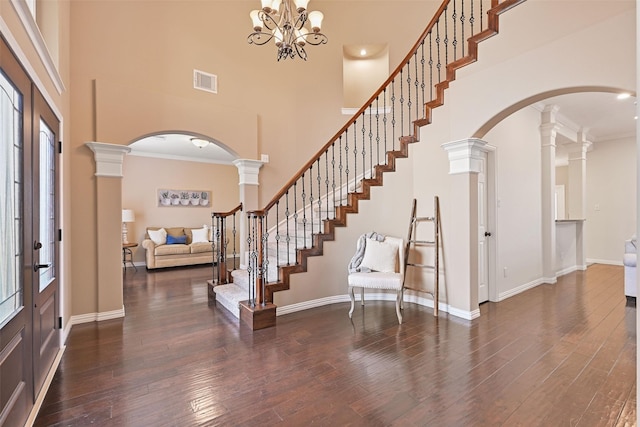 entryway with arched walkways, wood finished floors, a towering ceiling, and visible vents
