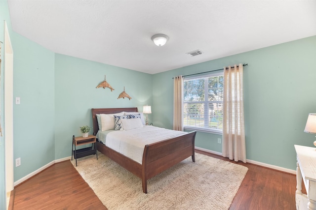 bedroom with baseboards, wood finished floors, and visible vents