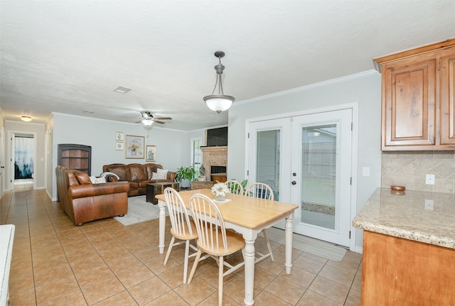 923 N Hull St, Caldwell, TX 77836 - dining space featuring light tile patterned flooring, a brick fireplace, a ceiling fan, french doors, and crown molding
