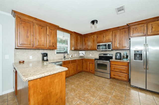 kitchen featuring tasteful backsplash, brown cabinetry, appliances with stainless steel finishes, visible vents, and a peninsula