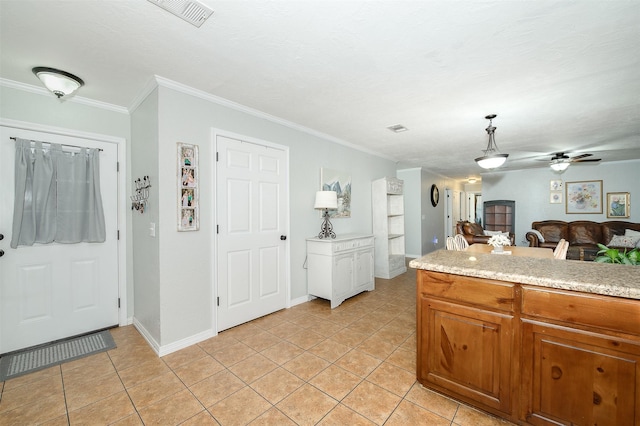 kitchen with visible vents, light tile patterned floors, ornamental molding, and light countertops