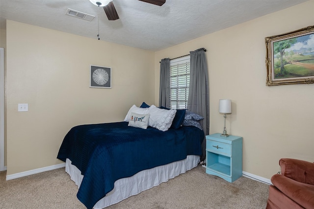 carpeted bedroom with a textured ceiling, visible vents, a ceiling fan, and baseboards