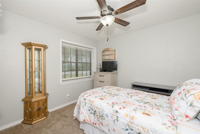 bedroom featuring light colored carpet, a ceiling fan, and baseboards