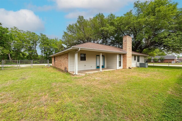 back of house with a patio, central air condition unit, a lawn, a chimney, and fence