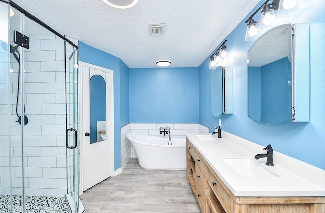 14619 Rosehill Dr, Houston, TX 77070 - full bath with a freestanding bath, a stall shower, double vanity, a textured ceiling, and wood finished floors