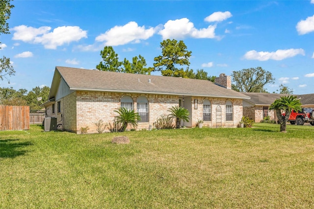 ranch-style house with a chimney, a front yard, fence, central AC, and brick siding