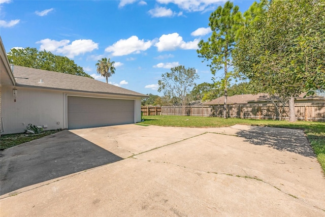 garage with concrete driveway and fence