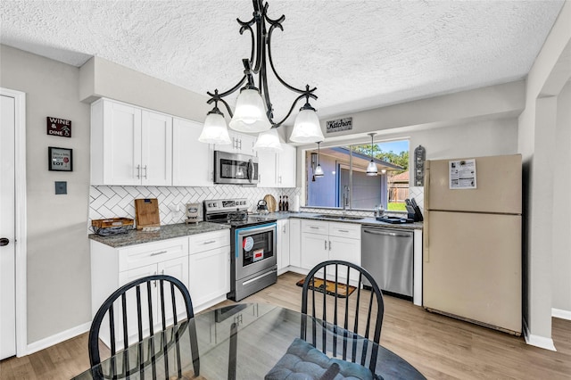 kitchen with stainless steel appliances, backsplash, white cabinets, and a sink