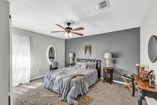 carpeted bedroom featuring a ceiling fan, visible vents, a textured ceiling, and baseboards