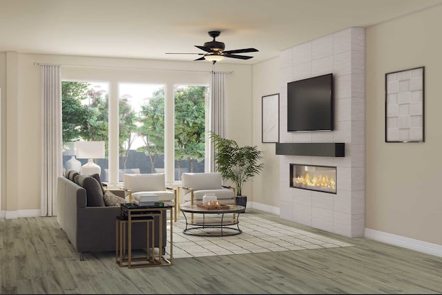 living room featuring baseboards, wood finished floors, a ceiling fan, and a fireplace