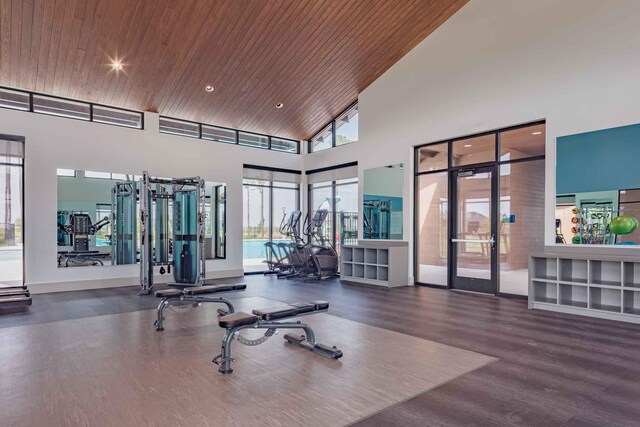 exercise room with a towering ceiling, wooden ceiling, wood finished floors, and french doors