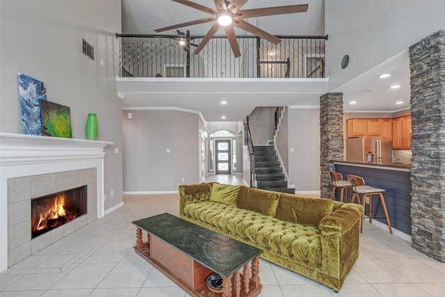 16015 Maycrest Ct, Tomball, TX 77377 - living room featuring a high ceiling, ceiling fan, a tiled fireplace, light tile patterned floors, and visible vents