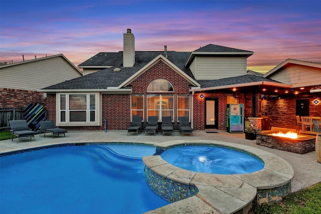 16015 Maycrest Ct, Tomball, TX 77377 - back of property at dusk featuring brick siding, a shingled roof, a patio area, and an outdoor fire pit