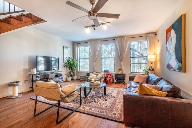 living area with track lighting, stairway, wood finished floors, and ceiling fan
