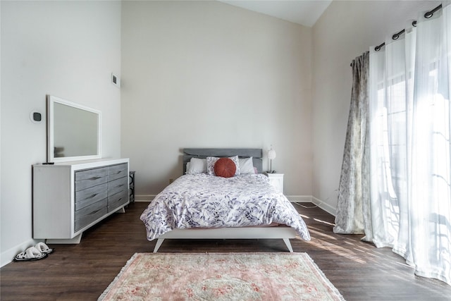 bedroom with high vaulted ceiling, dark wood finished floors, and baseboards