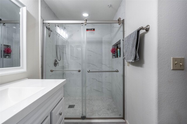 full bathroom with a marble finish shower and vanity