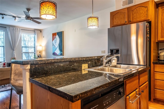 kitchen featuring light wood-style floors, a sink, visible vents, stainless steel refrigerator with ice dispenser, and dishwashing machine