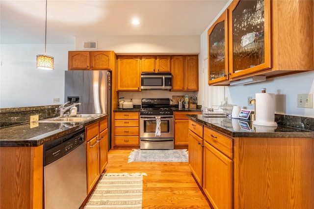 kitchen featuring brown cabinets, a sink, visible vents, stainless steel appliances, and light wood-style floors