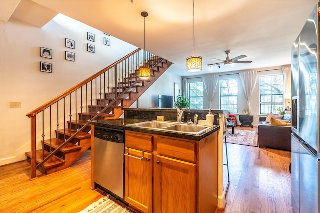 kitchen featuring a sink, stainless steel appliances, a ceiling fan, light wood-style flooring, and open floor plan