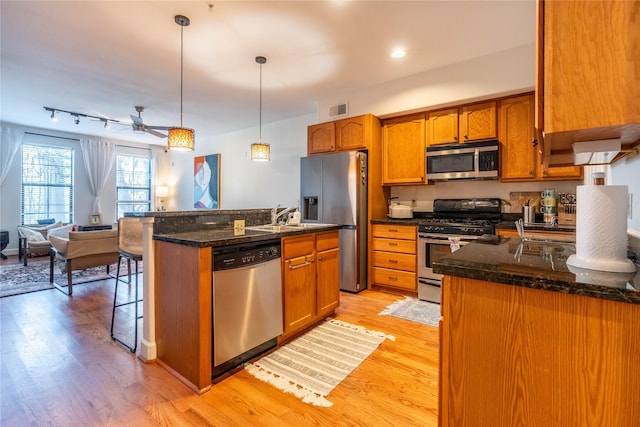 kitchen with light wood-type flooring, appliances with stainless steel finishes, and brown cabinets