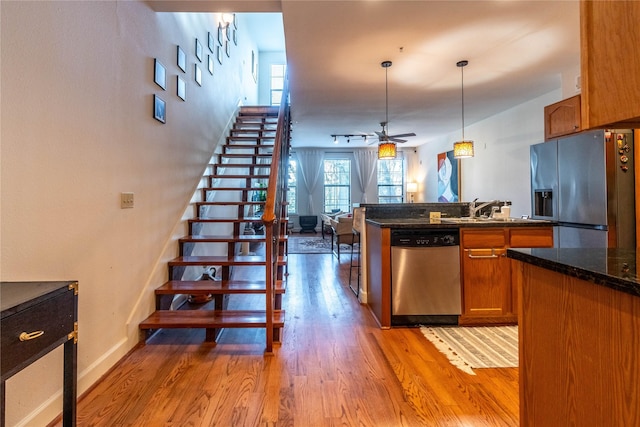 kitchen featuring stainless steel appliances, brown cabinets, ceiling fan, light wood finished floors, and a sink