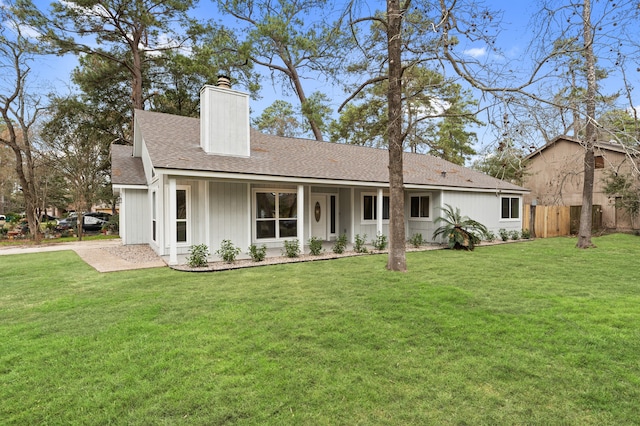 ranch-style house featuring a chimney, fence, a shingled roof, and a front lawn