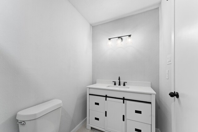 bathroom featuring toilet, vanity, and baseboards