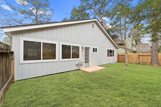 rear view of house with a fenced backyard and a lawn