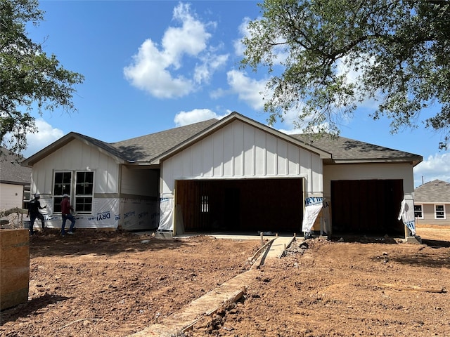 view of front facade with board and batten siding, a shingled roof, and an attached garage
