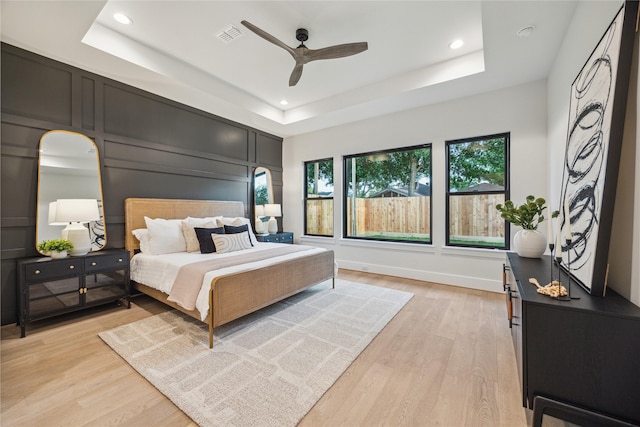 bedroom with recessed lighting, light wood-style flooring, and a raised ceiling