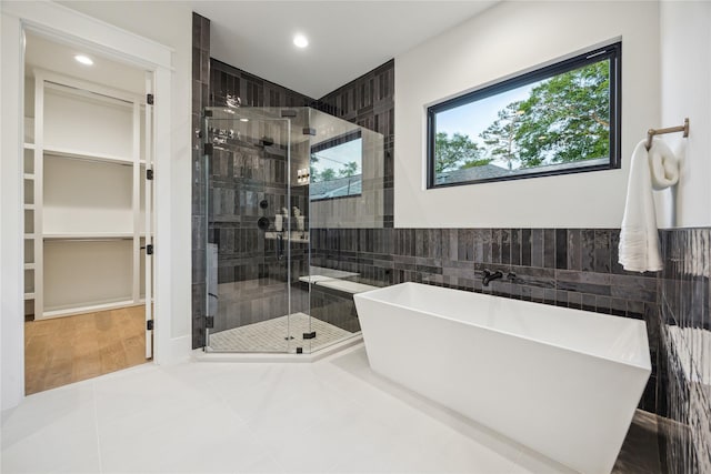 bathroom with a freestanding tub, tile walls, a shower stall, and recessed lighting