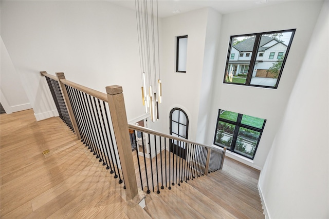 stairs featuring wood finished floors, a healthy amount of sunlight, and baseboards