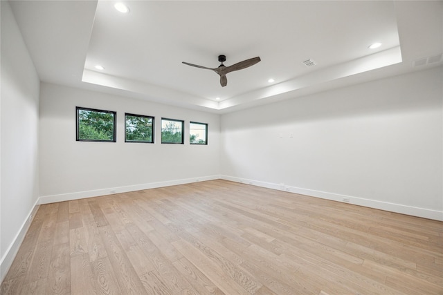 unfurnished room featuring light wood-type flooring, a raised ceiling, ceiling fan, and recessed lighting