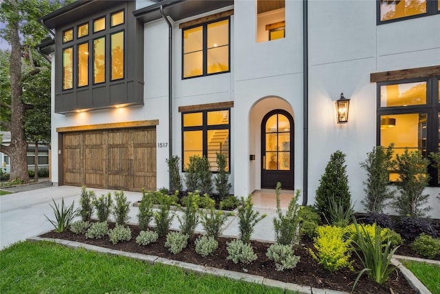view of front of house with an attached garage, driveway, stucco siding, and board and batten siding