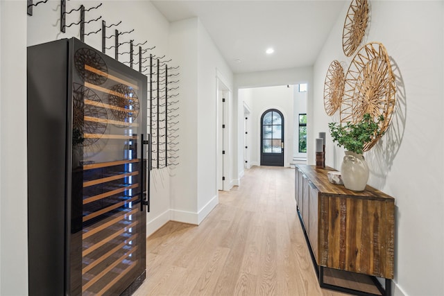 entryway with beverage cooler, baseboards, a dry bar, light wood-type flooring, and recessed lighting