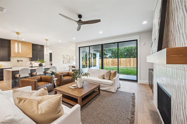 living area with a fireplace, a ceiling fan, light wood-style flooring, and recessed lighting