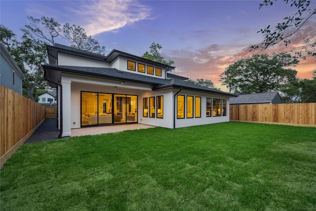 back of house featuring a yard, stucco siding, a fenced backyard, and a patio area