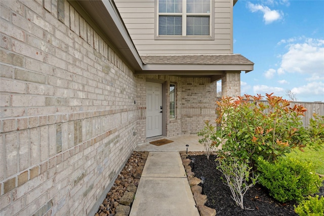 property entrance with brick siding and roof with shingles