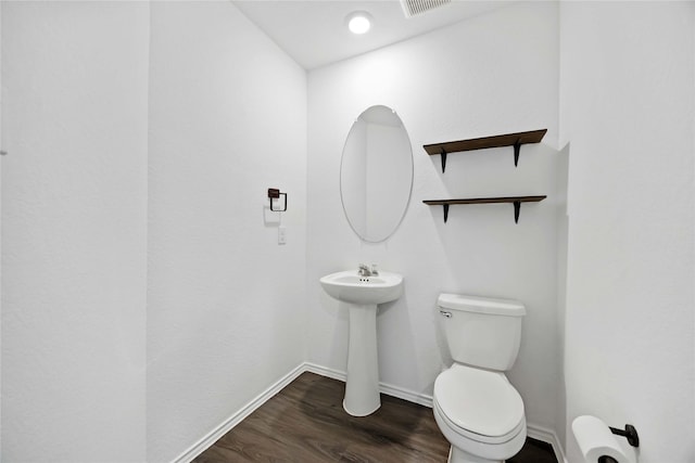 bathroom featuring visible vents, wood finished floors, a sink, baseboards, and toilet